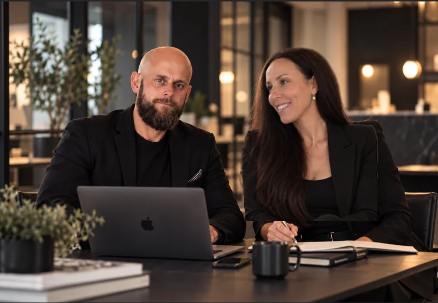 Timmi och Erika på Quma webbyrå diskuterar en ny webbdesign vid skrivbordet med laptop och skisser.